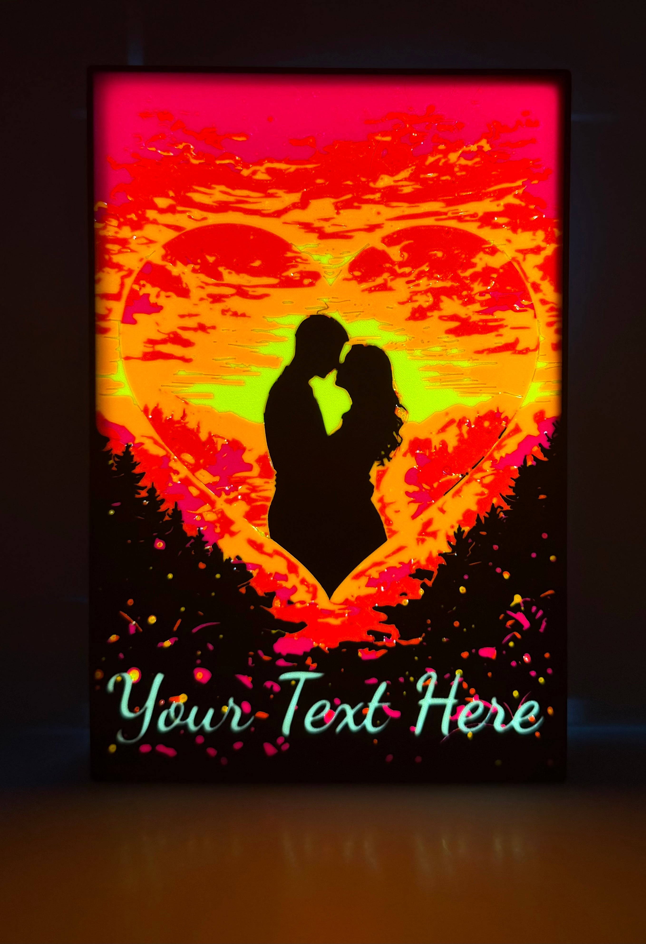 Heart-shaped Valentine's lightbox lit up showing pink and orange sunset gradient with couple